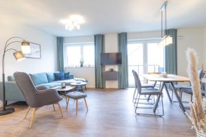 ein Wohnzimmer mit einer Couch und einem Tisch und Stühlen in der Unterkunft Ankerherz - besonders familienfreundlich, Hunde willkommen! in Kellenhusen