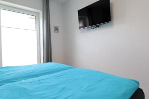 a bedroom with a bed and a flat screen tv on the wall at ROBERTA - mit Terrasse und Sauna in Diemelsee