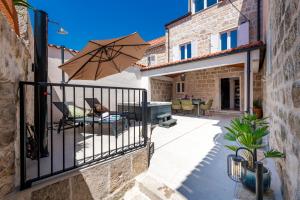 a balcony with an umbrella and a table and chairs at Villa Mareta Cavtat in Cavtat
