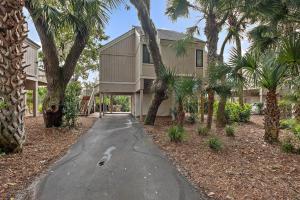 uma casa com palmeiras em frente a uma entrada em 818 Treeloft Cottage em Seabrook Island