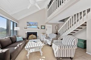 a living room with a couch and chairs and a staircase at 818 Treeloft Cottage in Seabrook Island
