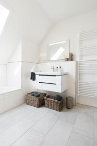 a white bathroom with a sink and a mirror at Meerperle - Sauna und überdachte Terrasse, Hunde willkommen! in Fedderwardersiel +21 photos