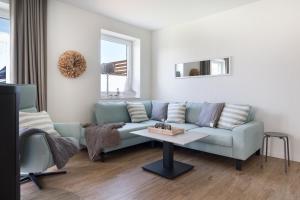a living room with a blue couch and a table at Meerperle - Sauna und überdachte Terrasse, Hunde willkommen! in Fedderwardersiel