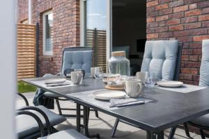 a table with plates and glasses on a patio at Meerperle - Sauna und überdachte Terrasse, Hunde willkommen! in Fedderwardersiel