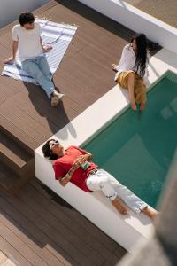 a group of people sitting around a swimming pool at Outsite Sagres in Sagres
