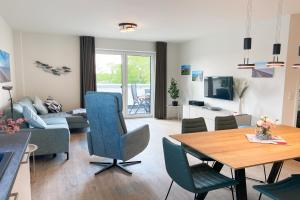 a living room with a table and a couch at KÜSTE33/48 – Penthousewohnung mit Dachterrasse, Sauna - strandnah! in Butjadingen OT Tossens