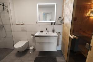 a white bathroom with a toilet and a sink at KÜSTE33/48 – Penthousewohnung mit Dachterrasse, Sauna - strandnah! in Butjadingen OT Tossens +20 photos
