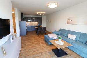 a living room with a blue couch and a table at KÜSTE33/20 – Exklusive Ferienwohnung mit Sauna & nah am Strand! in Butjadingen OT Tossens