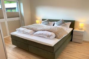 a bedroom with a bed with white sheets and pillows at KÜSTE33/23 – Seestern - Exklusive Ferienwohnung mit Sauna & nah am Strand! in Butjadingen OT Tossens