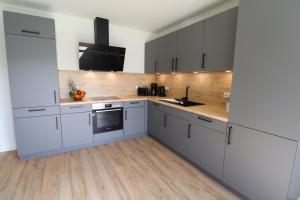 a kitchen with white cabinets and wooden floors at KÜSTE33/23 – Seestern - Exklusive Ferienwohnung mit Sauna & nah am Strand! in Butjadingen OT Tossens