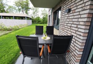 a table and chairs on a patio with a yard at KÜSTE33/23 – Seestern - Exklusive Ferienwohnung mit Sauna & nah am Strand! in Butjadingen OT Tossens