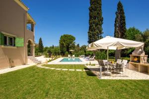 einem Pool mit Stühlen und einem Sonnenschirm neben einem Haus in der Unterkunft Villa Olga Corfu by Villa Plus in Kontokali