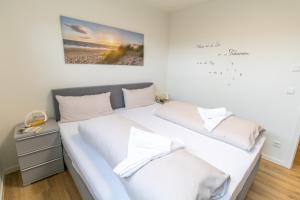 a bedroom with a large bed with white sheets at Küstenliebe Tossens – Exklusive Ferienwohnung mit Sauna & nah am Strand! in Butjadingen OT Tossens