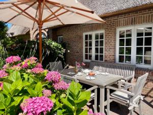 a table and chairs with an umbrella and flowers at Sylt Glück in Morsum