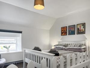 a white bedroom with a bed and a window at Cricketers Cottage in Ipstones +6 photos