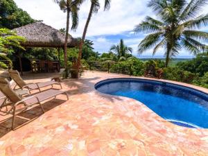 a swimming pool with two chairs and a umbrella at Privacy-waterfall-pool-sleeps 8-near Beach in Matapalo
