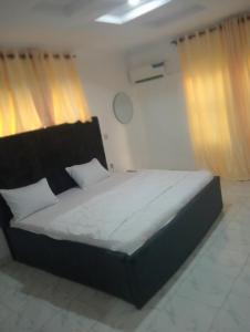 duże łóżko w pokoju z zasłonami w obiekcie fab shortlet apartment w mieście Lekki