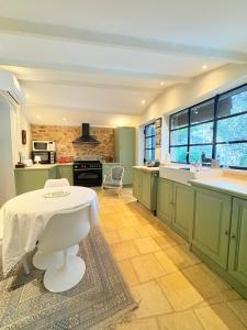 eine Küche mit grünen Schränken und einem weißen Tisch in der Unterkunft Les jardins de Montbazin in Montbazin + 10 Fotos