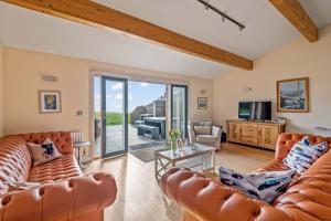 a living room with two leather couches and a television at House 36 in Looe
