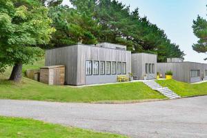 a large gray building with a tree and grass at House 47 in Talland