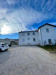 a white house with a car parked in front of it at Le petit Yvours, Irigny in Irigny