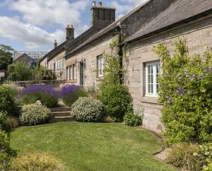an old stone house with a garden in front of it at Farm Cottage in Berwick-Upon-Tweed