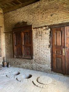 a room with a brick wall with a bed and a wooden door at Lurji Bani in Sighnaghi