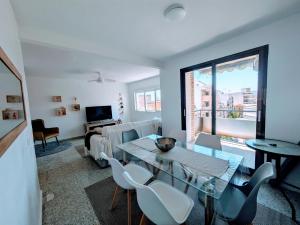 Una sala de estar con una mesa de cristal y sillas. en Casas Colores, en Villajoyosa