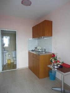cocina con armarios de madera y lavabo en una habitación en Galini Sea Apartments, en Benitses