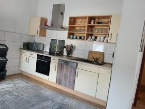 Eine Küche mit weißen Schränken und einem schwarzen Geschirrspüler in der Unterkunft Rosenberg in Kinheim