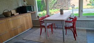 a kitchen with a wooden table and red chairs at De Âlde Bibleteek in Burgum +7 photos