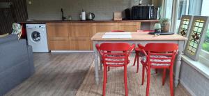 a kitchen with a table with four red chairs at De Âlde Bibleteek in Burgum