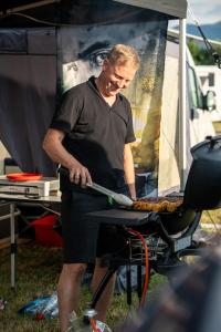 Un hombre cocinando comida en una parrilla dentro de una tienda de campaña. en Schitterhof CAMPING WEISS, en Spielberg