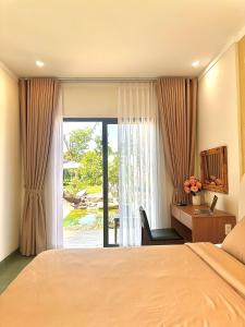una camera da letto con un letto, una scrivania e una finestra di NUBA Homestay and Coffee Buôn Ma Thuột a Buôn Ma Thuột