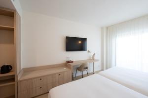 a bedroom with a bed and a desk and a television at Hotel RH Arena - Todo Incluido in Gandía