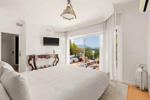 a white bedroom with a bed and a balcony at Molo Luxury Suites Puerto Banus in Marbella