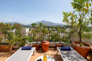 a balcony with tables and potted trees and mountains at Molo Luxury Suites Puerto Banus in Marbella