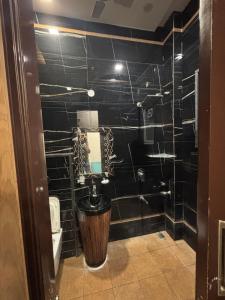 a bathroom with a toilet and a black tiled wall at SEVEN SEVEN HOMESTAy in Amritsar +45 photos