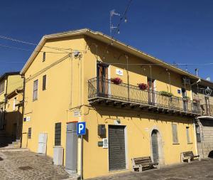 a yellow building with a balcony on top of it at Il Piazzale B&B in Filiano