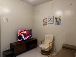 a living room with a flat screen tv and a chair at Cozy Brenthill Condo in Baguio City - Entire House Rental in Baguio