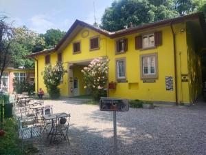 een geel huis met een bord ervoor bij New Generation Hostel Como Lake in Como