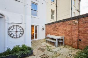 a clock on the side of a brick wall with a bench at Host & Stay - The Courtyard Retreat in Whitby