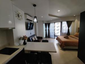a room with a bed and a kitchen with a table at Brenttstaycation at Tambuli Living Tower C,10D unit in Lapu Lapu City +3 photos