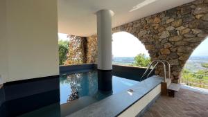 a bathroom with a plunge pool and a stone wall at Villa Bianca Luxury & Prestige in Massarosa
