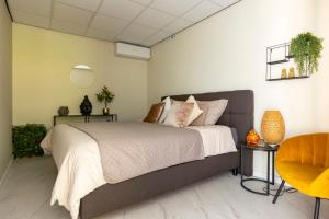 a bedroom with a large bed and a yellow chair at Wellness Studio Tiel met sauna en jacuzzi in Tiel +40 photos