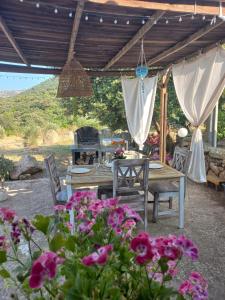 a patio with a table and chairs and flowers at Casa in campagna Su Frassu in Monti