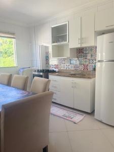 a kitchen with white cabinets and a table and chairs at Temporada Ilhéus 2/4 in Ilhéus