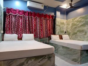 a room with two beds and a red curtain at Paribartan Hotel & Lodge in Farakka