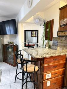una cocina con 2 taburetes y una barra en Cozy Apartment at Mystic Ridge Ocho Rios, en Ocho Ríos
