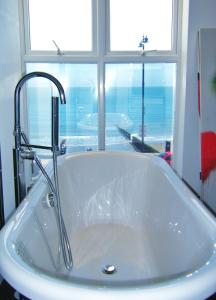 a bath tub with a faucet next to a window at shoreside inn in Shanklin